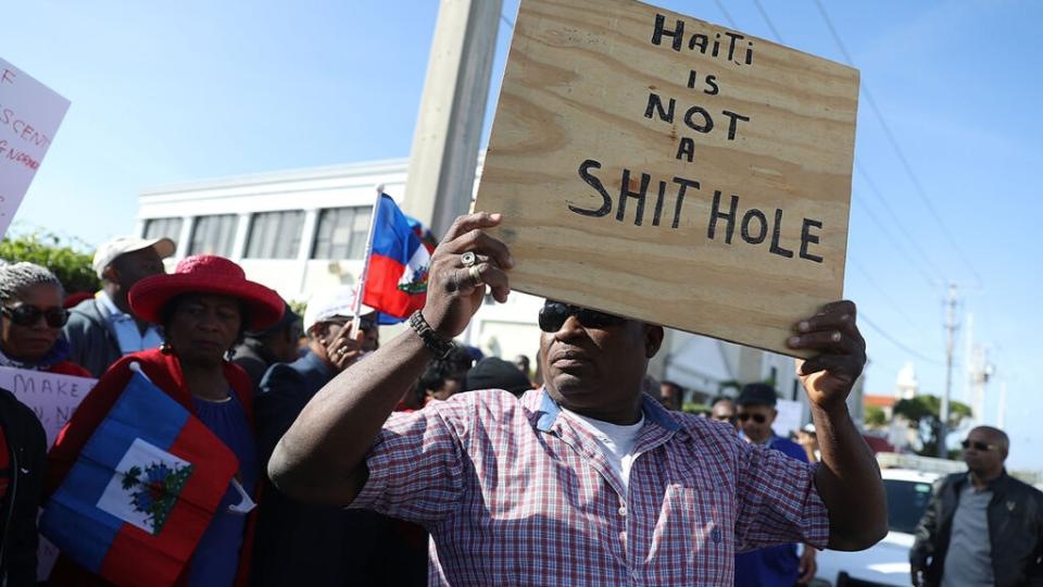 People join together, near the Mar-a-Lago resort where President Donald Trump spent the last few days, to condemn President Trumps reported statement about immigrants from Haiti and to ask that he apologize to them on January 15, 2018 in West Palm Beach, Florida. (Photo by Joe Raedle/Getty Images)