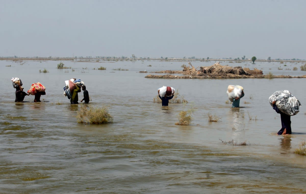 Victims of heavy flooding from monsoon rains crowd carry relief aid through flood water in Sindh Province (Fareed Khan/AP) File) (AP)