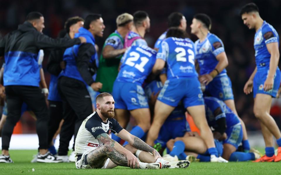 Sam Tomkins of England looks dejected following their side's defeat as Samoa celebrate