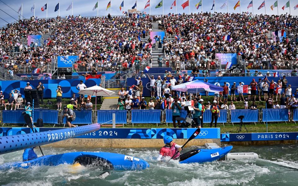 Taiwan's Wu Shao-hsuan performs an Eskimo roll as he competes against France's Titouan Castryck (R) in the men's kayak cross heats canoe slalom competition at Vaires-sur-Marne Nautical Stadium