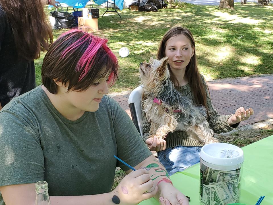 Alyse Yansling, Poppy the dog and Matilda Bergeron help in the kids craft area at the UFO Festival in Exeter Saturday, Sept. 3, 2022.