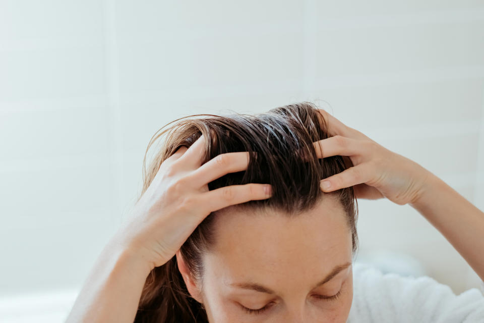 Woman delicately doing massage of her scalp with cosmetic oil