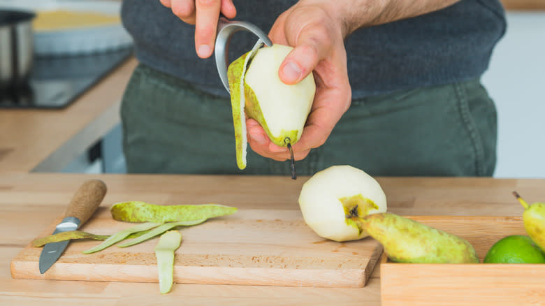Using peeler to remove pear skin