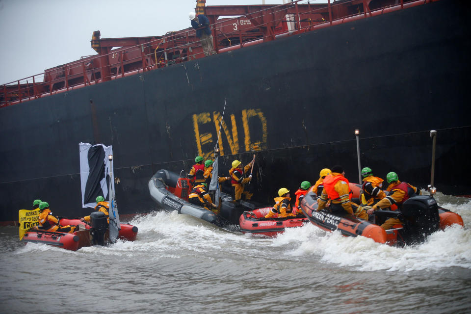 <p>Greenpeace activists write beside a banner with a silhouette of German Chancellor Angela Merkel onto the Golden Opportunity ship carrying coal as part of protests ahead of the upcoming G20 summit, in Hamburg Harbour, Germany July 2, 2017. (Hannibal Hanschke/Reuters) </p>