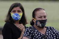 Supporters of Brazil's President Jair Bolsonaro wear face masks amid the new coronavirus pandemic decorated with his image during the president's departure from his official residence, Alvorada palace, Brasilia, Brazil, Monday, May 25, 2020. (AP Photo/Eraldo Peres)