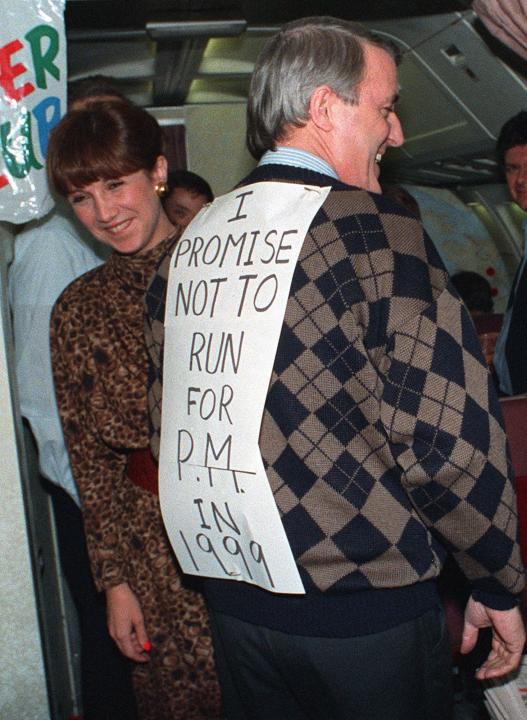 Prime Minister Brian Mulroney, supported by his wife Mila, jokes with the media trevelling on his campaign plane Nov. 22, 1988 during the flight home to Ottawa from  Baie Comeau.  Mulroney wore the sign that said he would not run in 1999, a response to questions earlier in the day regarding his intentions for a third term of office.