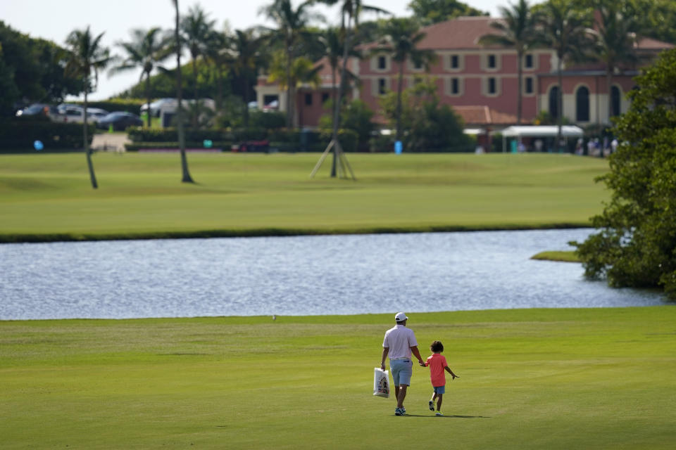 A man and child walk along the course during a practice day for the Walker Cup golf tournament at Seminole Golf Club in Juno Beach, Fla., Friday, May 7, 2021. (AP Photo/Gerald Herbert)