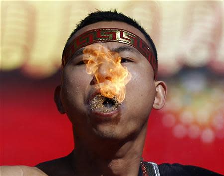 A man holds burning dry grass in his mouth while spitting a flame as he performs a feat of his strength during the opening of the temple fair for the Chinese New Year celebrations at Ditan Park, also known as the Temple of Earth, in Beijing January 30, 2014. REUTERS/Kim Kyung-Hoon