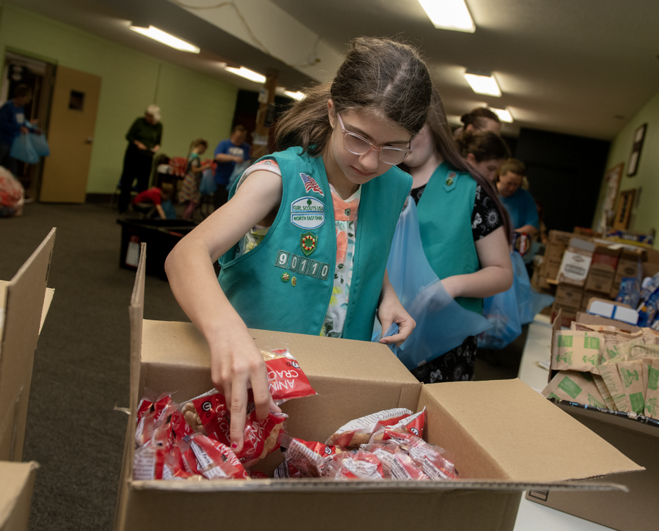 Lucy Tate, 10, with Girl Scout Troop 90110, fills a Raven Pack at Portage Community Chapel in Ravenna on April 27.