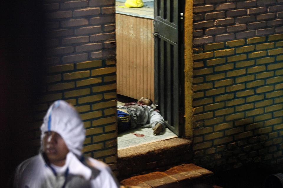 A body is stretched out at the door of a bar in the community of Comayaguela, Honduras, Friday, Oct. 19, 2018. At least eight people were killed and two other wounded at the bar Friday, according to the police. (AP Photo/Fernando Antonio)