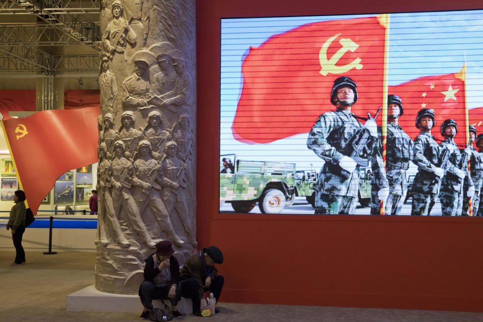 Thursday, Oct. 19, 2017, photo, an elderly couple rests under a screen showing Chinese soldiers posing with the Communist Party flag at an exhibition highlighting China's achievements under five years of his leadership at the Beijing Exhibition Hall in Beijing. Xi is channeling a red-blooded nationalism as he seeks to strengthen the Communist Party's role in Chinese life and assert Beijing's rise as a global superpower. Xi's muscular foreign policy could become even more assertive following this month's party congress, where he's expected to get a second five-year term as party secretary general. (AP Photo/Ng Han Guan)