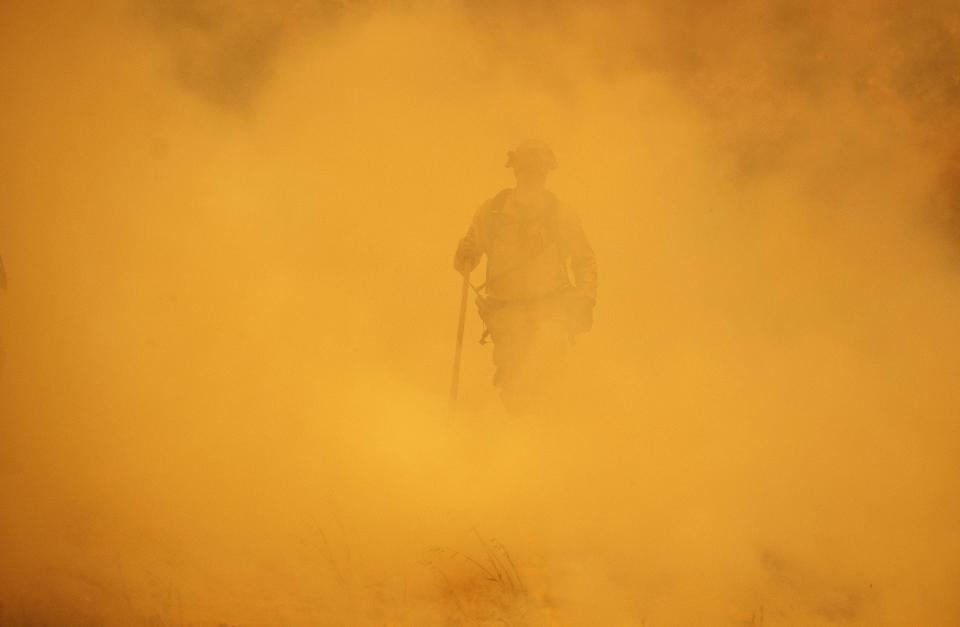 A firefighter walks through smoke during the Mendocino Complex Fire in Lakeport.