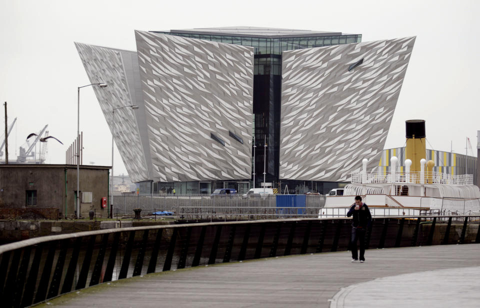 FILE - In this Tuesday March 13, 2012 file photo, a man walks past the new Titanic Belfast Visitor's Center in Northern Ireland, opening March 31 near the defunct shipyard where the doomed ocean liner was built 100 years ago. Titanic artifacts, models, tours and talks are taking place in many parts of England and North America to mark the centennial of the ship’s April 15 sinking.(AP Photo/Peter Morrison, File)