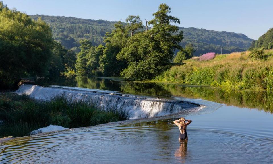 A swimmer standing in the shallows of the River Avon at Warleigh Weir in Somerset, England.