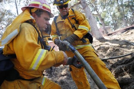 Firefighters repair a punctured hose while mopping up hotspots during the Clayton Fire at Lower Lake in California, U.S. August 15, 2016. REUTERS/Stephen Lam