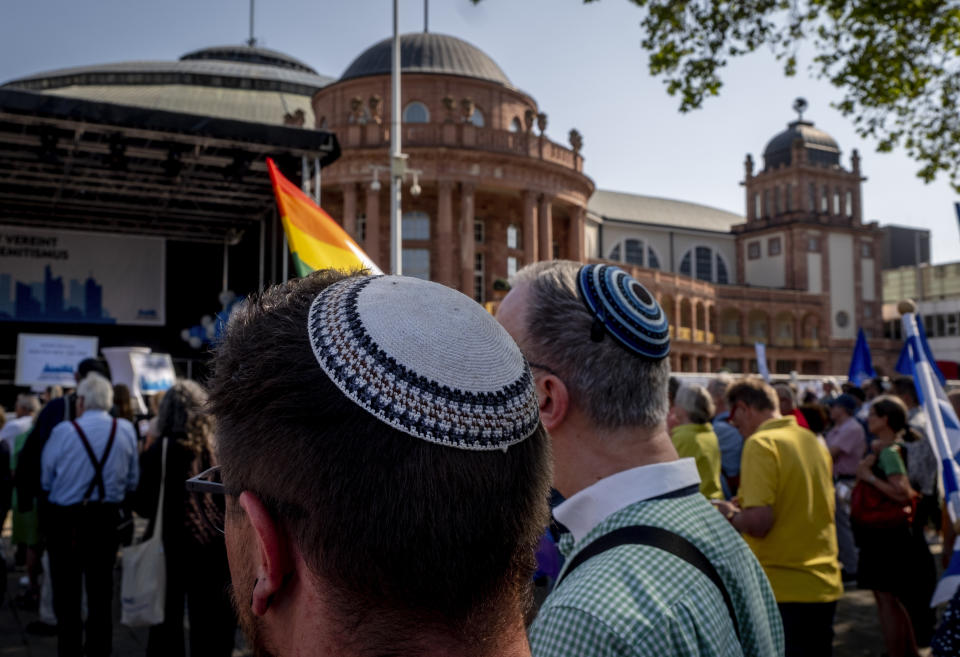 Two men wearing kips take part in a demonstration against a concert later the day of former Pink Floyd musician Roger Waters in the Festhalle, background, in Frankfurt, Germany, Sunday, May 28, 2023. The Festhalle was the the place where in the night of broken glasses 1938 about 3000 Jewish men where gathered to deport them to concentration camps. (AP Photo/Michael Probst)