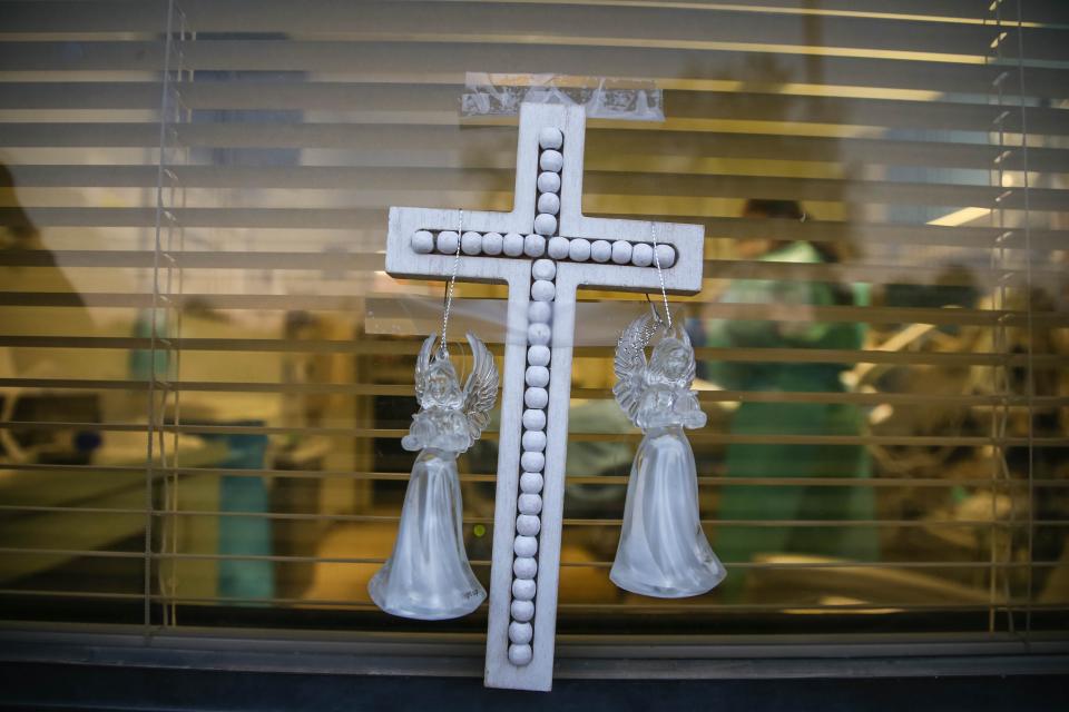 A cross and angels are placed outside a COVID-19 patient's hospital room at Memorial Medical Center in Las Cruces, N.M. on Monday, Nov. 30, 2020.