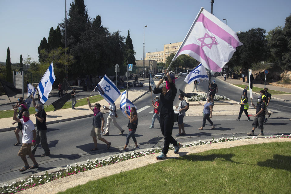 Israeli protesters wave flags and chant slogans during a demonstration against a proposed measure to curtail public demonstrations during the current nationwide lockdown due to the coronavirus pandemic, in front of the Knesset, Israel's parliament in Jerusalem, Tuesday, Sept. 29, 2020. (AP Photo/Sebastian Scheiner)