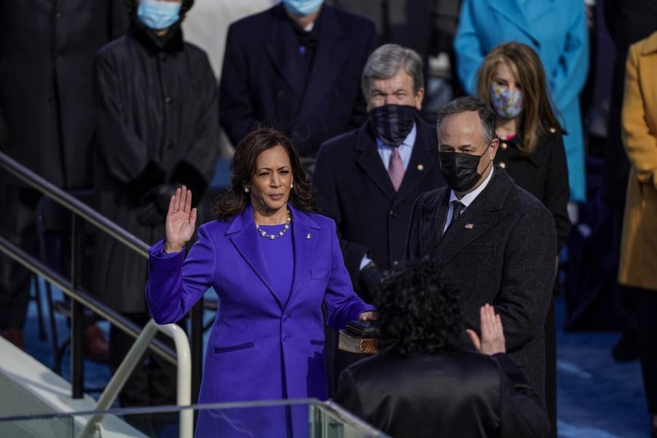 Kamala Harris raises her hand as Supreme Court Justice Sonia Sotomayor raises hers and Harris' husband is beside her.