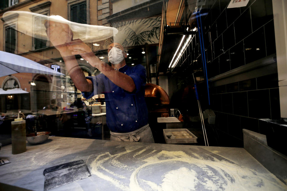 A pizza maker prepares a pizza in a restaurant in downtown Rome, Sunday, Oct. 25, 2020. For at least the next month, people outdoors except for small children must now wear masks in all of Italy, gyms, cinemas and movie theaters will be closed, ski slopes are off-limits to all but competitive skiers and cafes and restaurants must shut down in early evenings, under a decree signed on Sunday by Italian Premier Giuseppe Conte, who ruled against another severe lockdown despite a current surge in COVID-19 infections. (Cecilia FabianoLaPresse via AP)