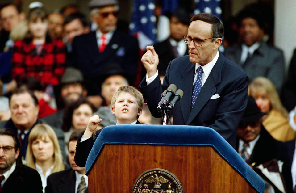 FILE - In this Jan. 2, 1994 file photo, Andrew Giuliani, left, gestures while his father, New York Mayor Rudolph Giuliani addresses the crowd after being sworn-in as the 107th mayor of New York City. Andrew Giuliani announced Tuesday, May 18, 2021, that he is seeking the Republican nomination for governor of New York, potentially setting up a battle with third-term incumbent Democrat Andrew Cuomo. (AP Photo/Mark Lennihan, File)