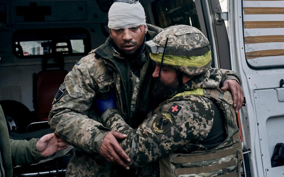 A Ukrainian soldier helps a wounded comrade at a hospital in Bakhmut, Donetsk region - Libkos/AP