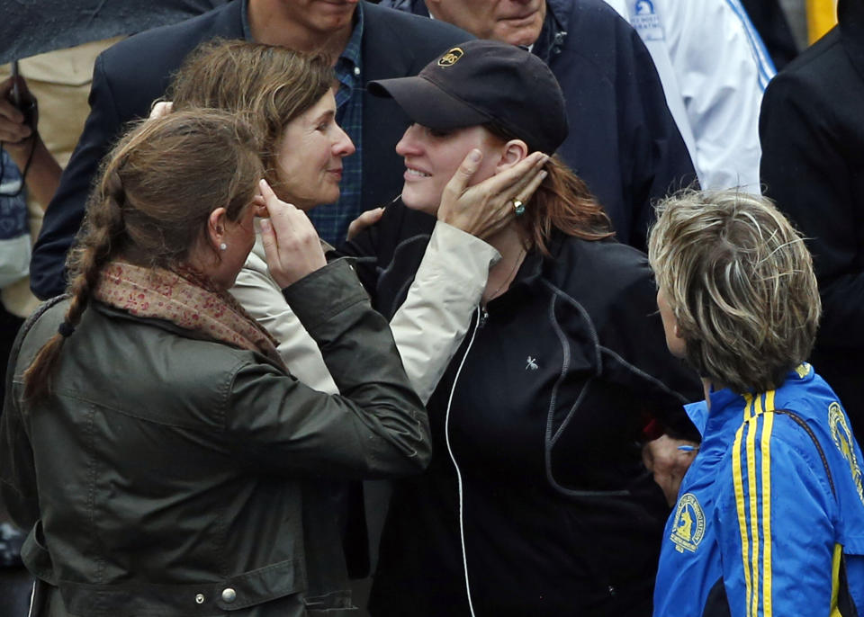 2013 Boston Marathon bombing survivor Erika Brannock, in hat, a pre-school teacher from the Baltimore area, is embraced as she walks across the Marathon finish line after a remembrance ceremony on Boylston Street in Boston, Tuesday, April 15, 2014. (AP Photo/Elise Amendola)