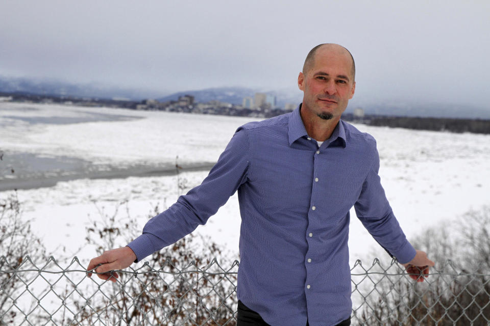 FILE - This Jan. 13, 2022, photo shows Harlow Robinson posing for a photo with downtown Anchorage, Alaska, behind him. Robinson supported a successful ballot initiative passed by Alaska voters in 2020 that would end party primaries and send the top four vote-getters, regardless of party affiliation, to the general election, where ranked-choice voting would determine a consensus winner. The Alaska Supreme Court is set to hear a challenge to the system Tuesday, Jan. 18, 2022. (AP Photo/Mark Thiessen, File)