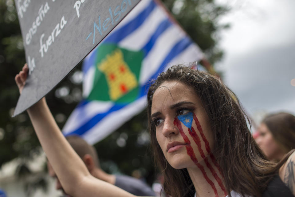 In this July 25, 2019 photo, a young woman takes part in the festivities to celebrate the resignation of Gov. Ricardo Rossello, after weeks of protests over leaked obscene, misogynistic online chats, in San Juan, Puerto Rico. Puerto Ricans are now debating how to rid the territorial government of corruption while harnessing the energy that still remains from the massive protests that led to the governor's resignation. (AP Photo/Dennis M. Rivera Pichardo)