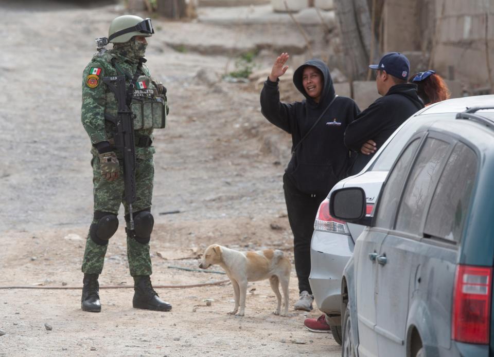 A Mexican soldier speaks to residents near the home where two bodies were removed by Mexican coroner officials from a narco grave on Thursday in Juárez.