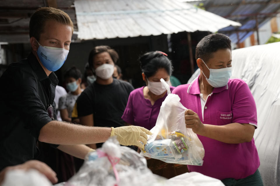 Bangkok Community Help Foundation co-founder Friso Poldervaart, left, from the Netherlands distributes food supplies at a construction camp in Bangkok, Thailand, on Aug. 31, 2021. In Thailand’s worst coronavirus surge yet, lockdown measures have reduced what little Bangkok’s have-nots had to zero. Their plight has given rise to volunteer groups working to ensure the poorest survive. (AP Photo/Sakchai Lalit)