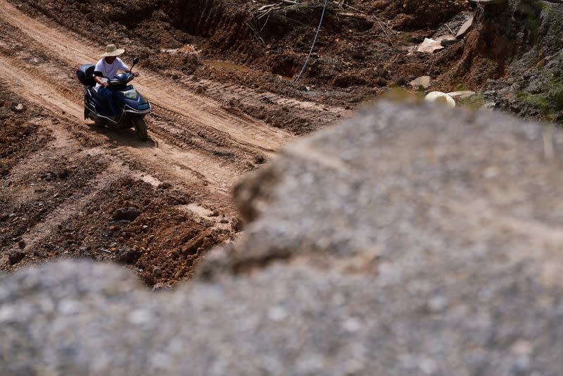 Man rides a vehicle at a dam that collapsed following heavy rainfall at the Shazixi reservoir in Yangshuo