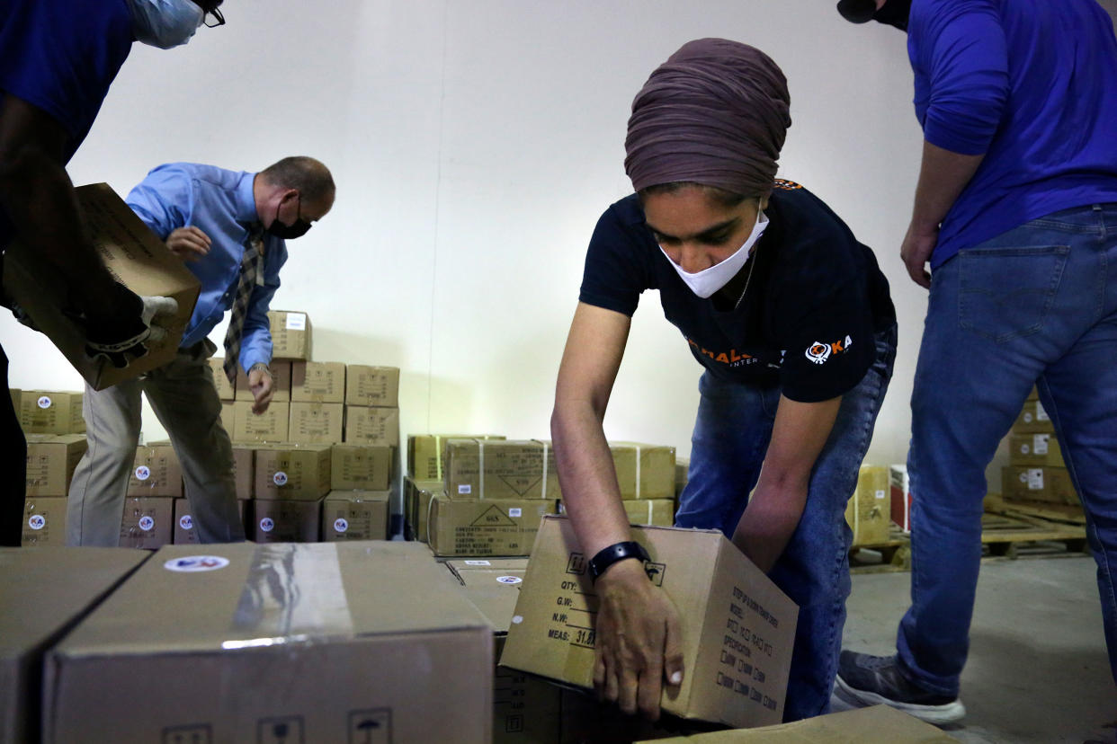 Tim Williams, warehouse assistant for Medisys, Ray Fredericks, assistant director for Medisys, Dr. Abhu Kaur with Khalsa Aid, and Michael Stack, healthcare account representative for Grainger, load dozens of electrical transformers onto a pallet to be shipped from New York to New Delhi, along with oxygen concentrators, on May 7, 2021.