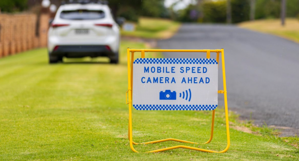 A mobile speed detection sign is seen in front of white mobile detection vehicle. 