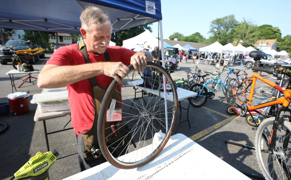 Steve Christensen, lead mechanic, replaces a tire tube on a bicycle at the always-busy R Community Bikes repair stand at the Westside Farmers Market.  The bike stand provides free bike repairs to customers of all ages who stop in.