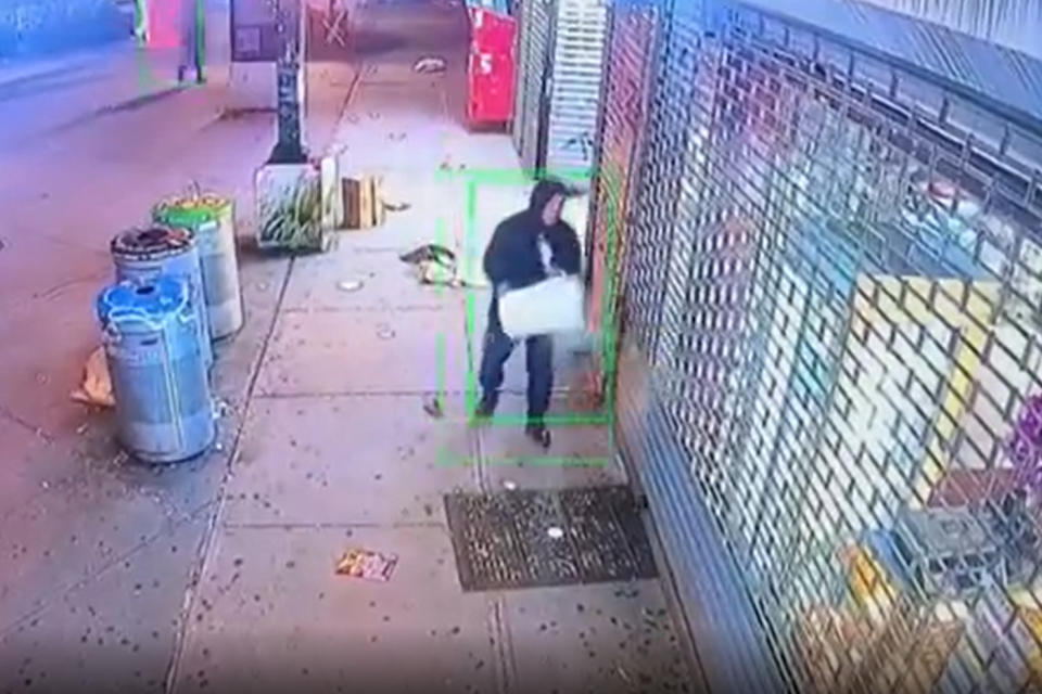 A man appears to throw a liquid substance in front of a restaurant before setting it on fire in Queens, N.Y. (NYFD)