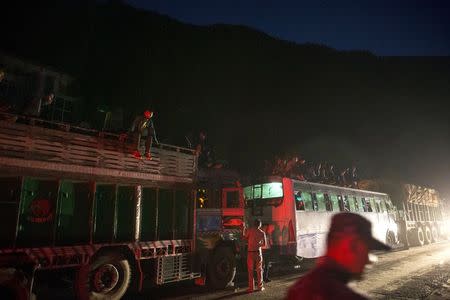 People ride on buses as traffic is affected by a landslide caused by an earthquake, in Kurintar, Nepal April 27, 2015. REUTERS/Athit Perawongmetha