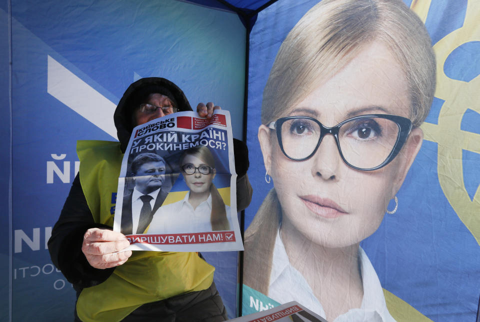 An agitator holds a paper reading "What country will we wake up in?" as she sits inside a campaigning tent of presidential candidate Yulia Tymoshenko, Ukraine's former prime minister, in Kiev, Ukraine, Thursday, March 28 2019. Ukraine will vote for the new president on March 31 (AP Photo/Efrem Lukatsky)