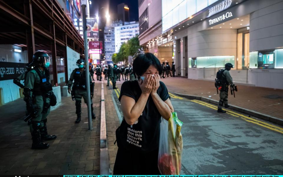 A woman covers her mouth as riot police fire pepper ball projectiles during a rally against a new national security law on Wednesday's 23rd anniversary of the city's handover from Britain to China  - Billy HC Kwok /Getty 