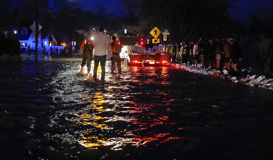 People work to protect homes into the night along 1700 South in Salt Lake City from the rising flow of Emigration Creek through Wasatch Hollow Park on Wednesday, April 12, 2023. As rapid snowmelt and possible April showers stoke fears of heavy flooding in the Northern Plains, state officials are announcing flood response plans, and residents are assembling thousands — if not hundreds of thousands — of sandbags to combat floods themselves. (Francisco Kjolseth/The Salt Lake Tribune via AP)