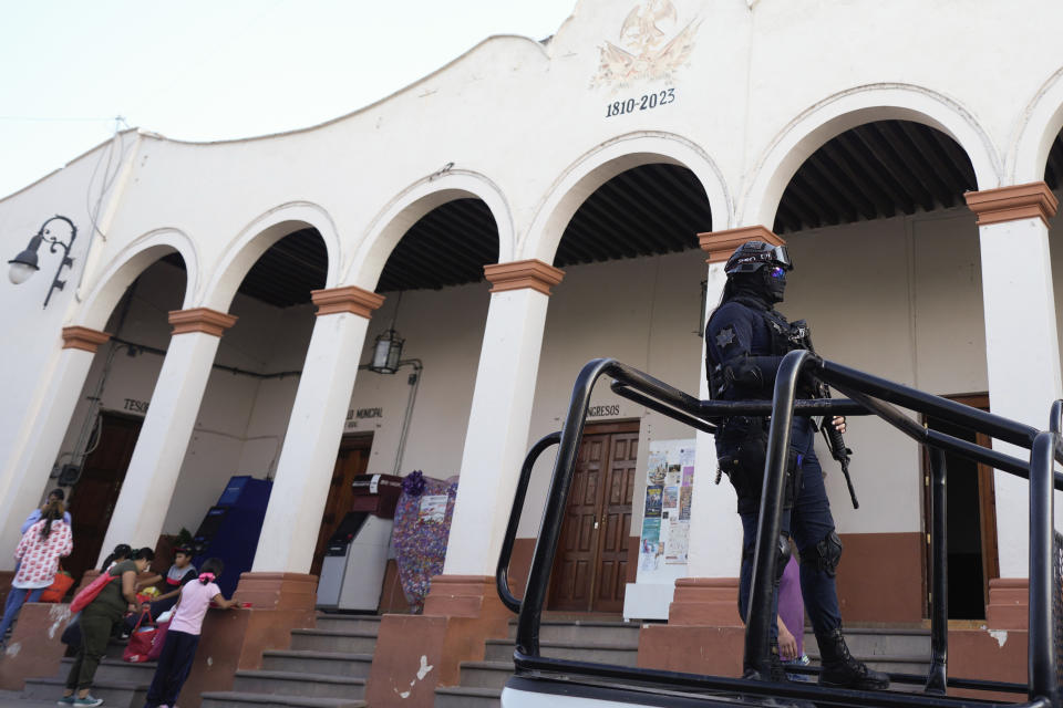 An officer rideson a police vehicle past the City Hall in Maravatio, Michoacan state, Mexico, on Tuesday, Feb. 27, 2024. Two mayoral hopefuls in this city were gunned down the previous day within hours of each other. (AP Photo/Fernando Llano)