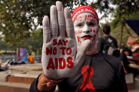 FILE PHOTO: A man poses as he displays his hand and face painted with messages during an HIV/AIDS awareness campaign on the eve of World AIDS Day in Kolkata, India, November 30, 2018. REUTERS/Rupak De Chowdhuri/File Photo