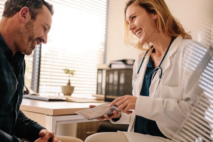 Doctor using a tablet to show a patient his test results.