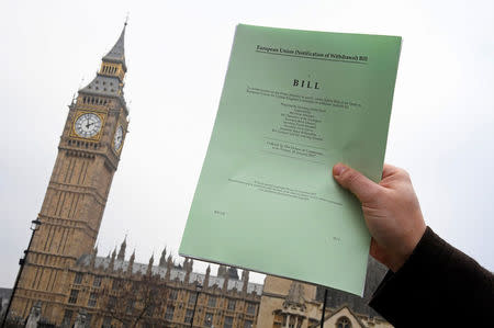 FILE PHOTO: A journalist poses with a copy of the Brexit Article 50 bill, introduced by the government to seek parliamentary approval to start the process of leaving the European Union, in front of the Houses of Parliament in London, Britain, January 26, 2017. REUTERS/Toby Melville/File Photo