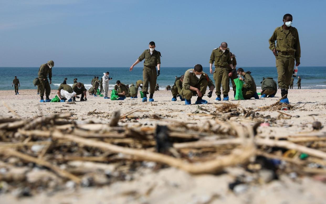 Israeli soldiers search for tar grains while cleaning the Palmachim Beach near the city of Rishon Lezion - ABIR SULTAN/EPA-EFE/Shutterstock 