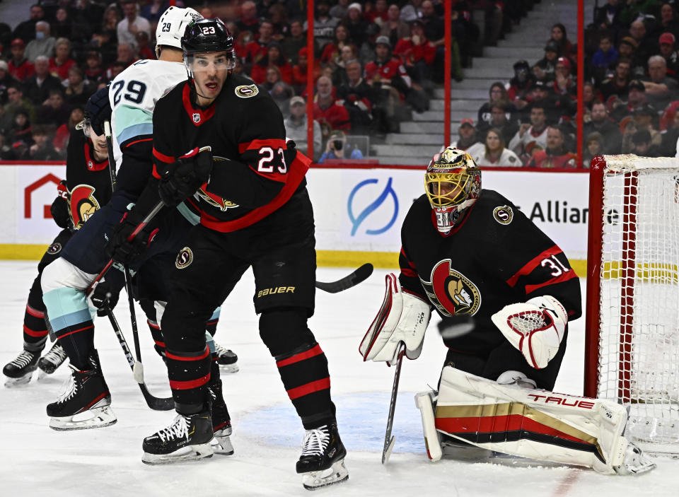 A rebound bounces away from Ottawa Senators goaltender Anton Forsberg (31) as defenseman Travis Hamonic (23) and Seattle Kraken defenseman Vince Dunn (29) play in front of the net during first-period NHL hockey game action in Ottawa, Ontario, Saturday, Jan. 7, 2023. (Justin Tang/The Canadian Press via AP)