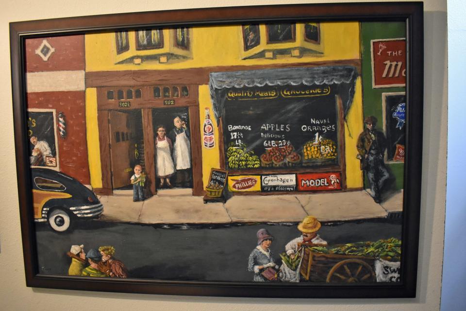 A painting by Joe Geha depicts his parents' grocery store in Toledo, Ohio, with his mom and dad shown in the doorway and a young Joe on the sidewalk.