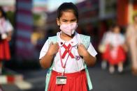 A girl arrives to school wearing a protective mask on Valentine's Day in Ayutthaya, outside Bangkok