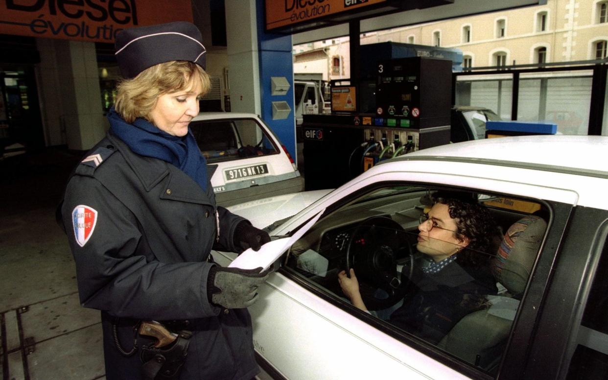 A policewoman verifies the ID of a driver in a gas station - JEAN-PAUL PELISSIER/Reuters