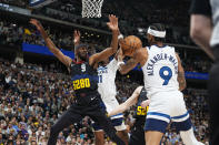 Minnesota Timberwolves guard Nickeil Alexander-Walker, right, steals the ball from Denver Nuggets forward Justin Holiday, left, who was driving to the basket past Timberwolves center Naz Reid, second from left, in the first half of Game 2 of an NBA basketball second-round playoff series Monday, May 6, 2024, in Denver. (AP Photo/David Zalubowski)